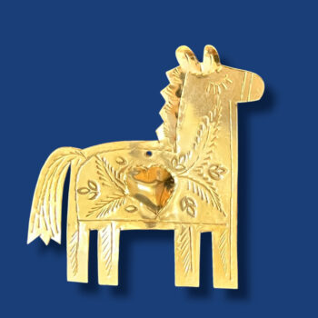 Cheval décoratif en laiton gravé à la main, suspendu sur un mur blanc, mettant en valeur les motifs artisanaux marocains