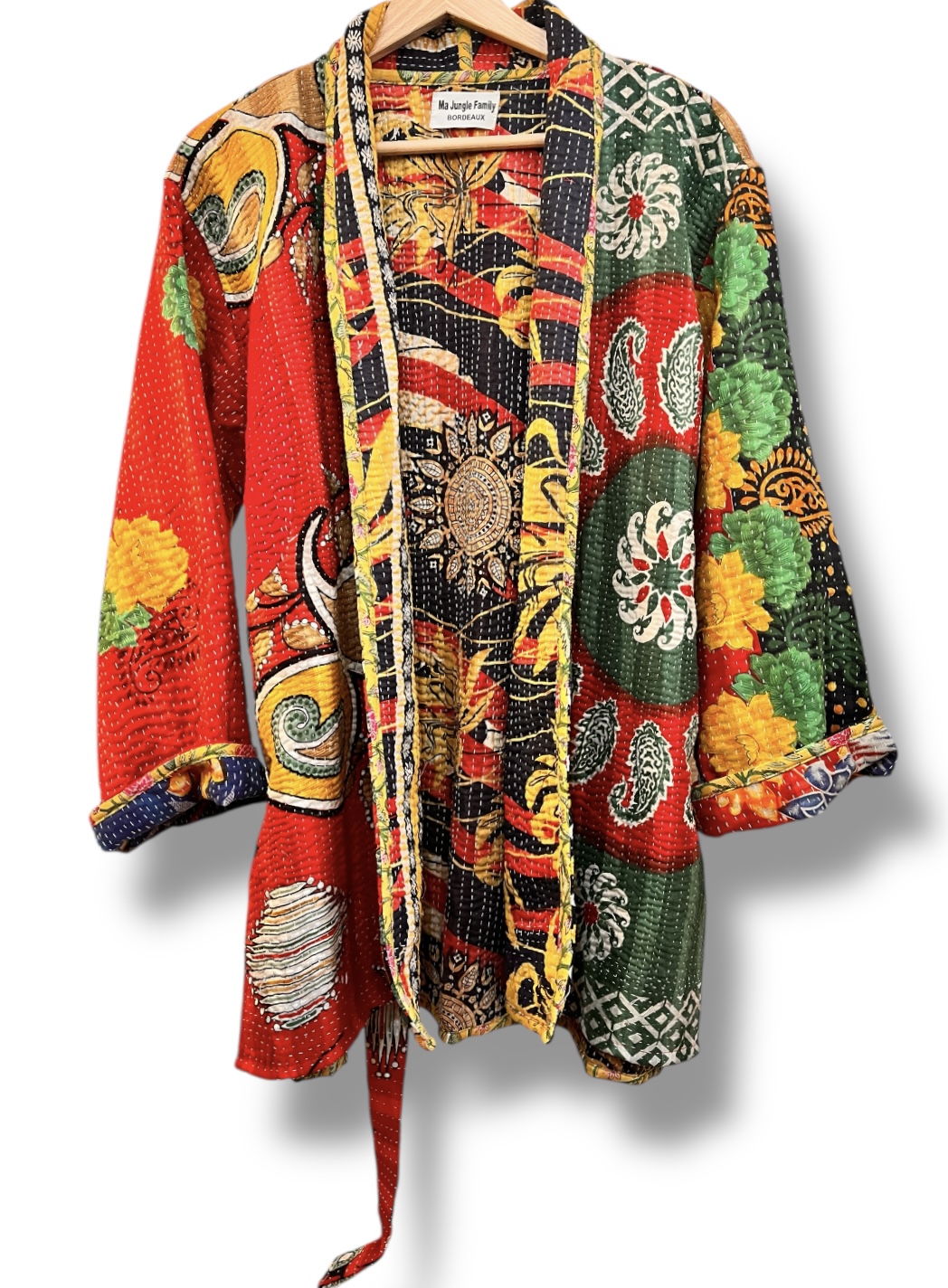 Veste kantha vintage réversible en coton recyclé, faite main à partir de saris indiens – pièce unique aux motifs fleuris colorés, exposée sur un portant. Rouge, vert, fleurs