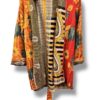 Veste kantha vintage réversible en coton recyclé, faite main à partir de saris indiens – pièce unique aux motifs fleuris colorés, exposée sur un portant. Rouge, vert, fleurs, orange, reversilble