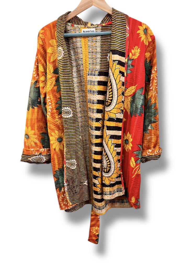 Veste kantha vintage réversible en coton recyclé, faite main à partir de saris indiens – pièce unique aux motifs fleuris colorés, exposée sur un portant. Rouge, vert, fleurs, orange, reversilble