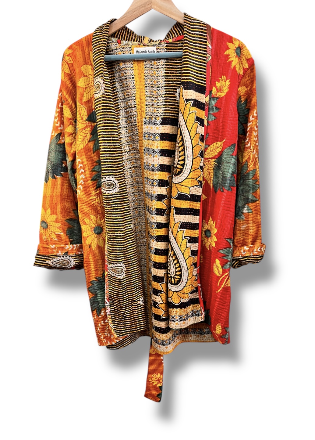 Veste kantha vintage réversible en coton recyclé, faite main à partir de saris indiens – pièce unique aux motifs fleuris colorés, exposée sur un portant. Rouge, vert, fleurs, orange, reversilble