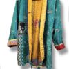 Veste kantha vintage réversible en coton recyclé, faite main à partir de saris indiens – pièce unique aux motifs fleuris colorés, exposée sur un portant. Rouge, vert, fleurs, orange, reversilble, turquoise, jaune, upcycling