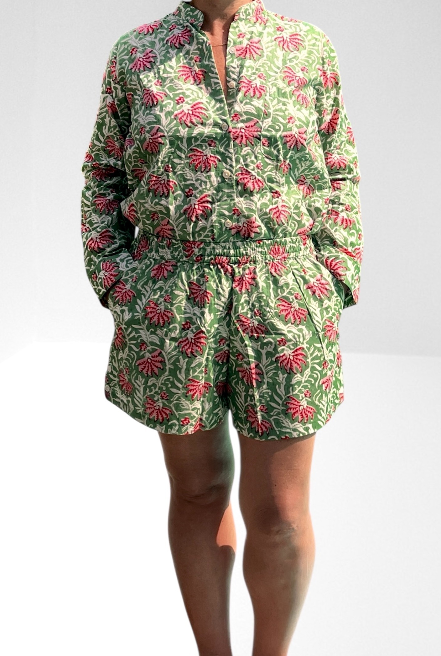 Cet ensemble unique associe le charme de l’artisanat indien et le savoir-faire de notre atelier bordelais. La chemise à col Mao, élégamment boutonnée avec de sublimes boutons en nacre, est imprimée à la main selon la technique ancestrale du block print en Inde. Le short assorti reprend les mêmes imprimés et se distingue par ses finitions soignées : poches latérales et arrières, petits boutons délicats sur les côtés, cuisses en nacre… chaque détail compte. Un look à la fois décontracté et raffiné, pensé pour celles qui aiment porter des pièces uniques, responsables et empreintes de voyage. Créé avec amour à Bordeaux, fabriqué à la main entre ici et ailleurs. Tissu fleuri vert et rose