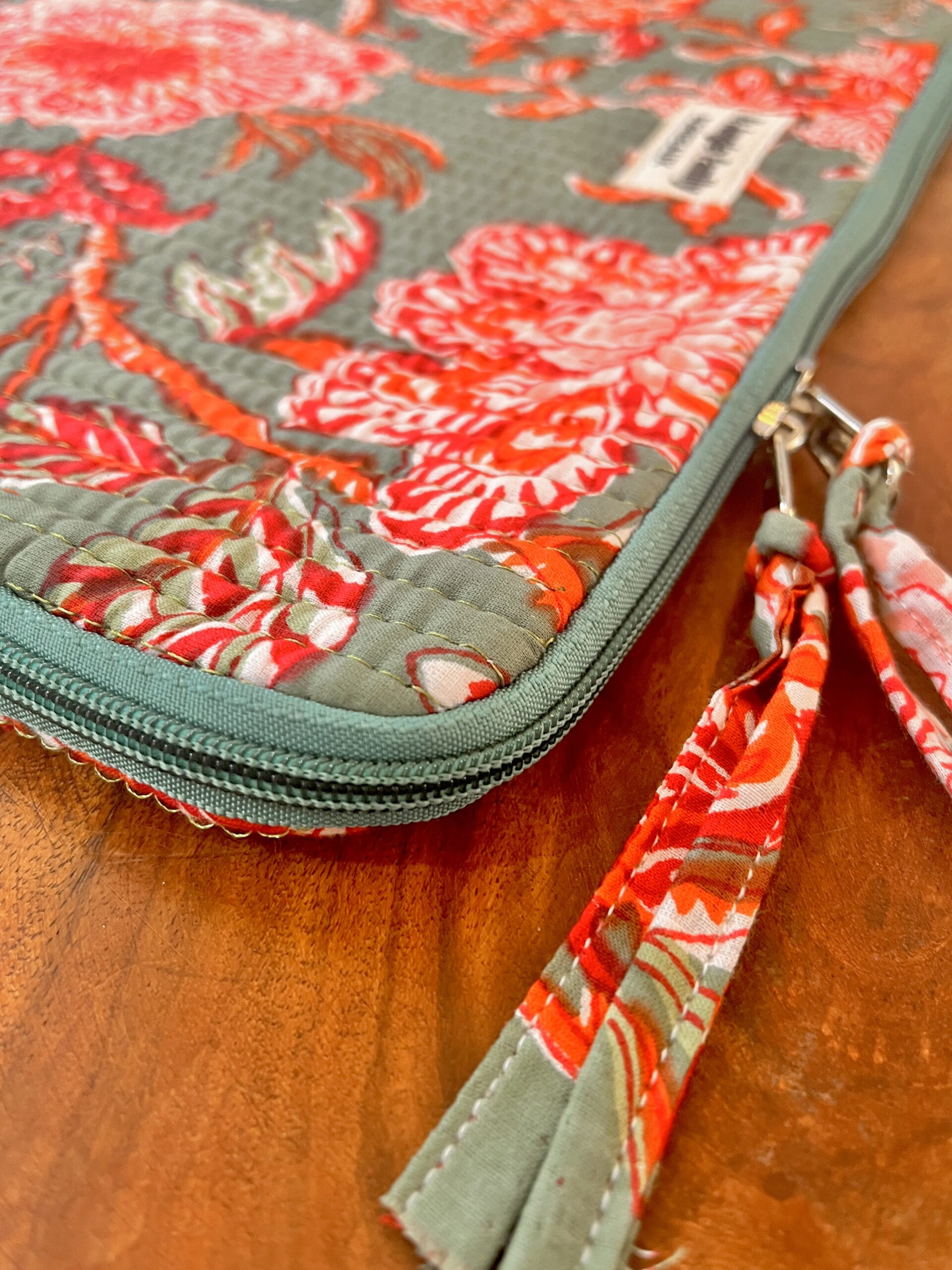 Housse d’ordinateur en coton indien matelassé avec imprimé floral block-print, format 15 pouces, faite main. Housse d’ordinateur artisanale en coton indien, motif original, utilisée pour transporter un laptop, Accessoire éthique : housse ordinateur bohème en coton imprimé, tenue à la main dans un décor naturel. Housse d’ordinateur Ma Jungle Family – coton indien artisanal – Bordeaux Fleuriste colorés hibiscus vert et orange